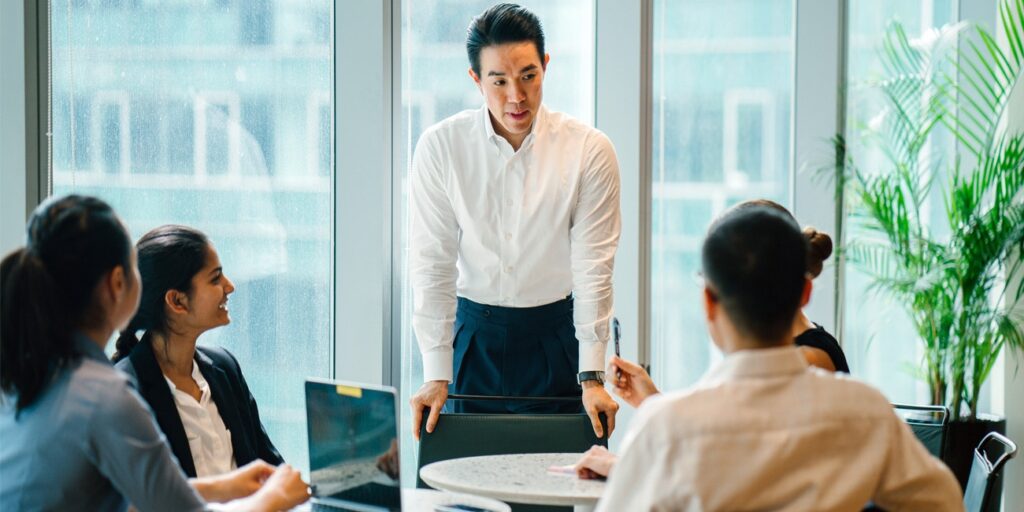 Asian male leader motivates team of diverse coworkers